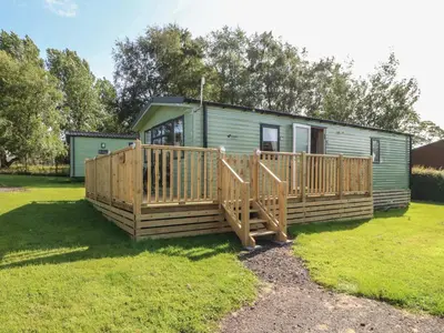 a small green caravan with a wooden deck at Barney's Retreat - Docker Park Farm in Carnforth
