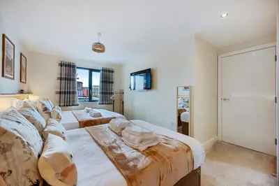 a bedroom with two beds and a tv on the wall at Spectacular Central Apartment Free Parking Sleep 7 in Liverpool