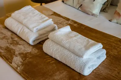 three white towels sitting on a wooden cutting board at Spectacular Central Apartment Free Parking Sleep 7 in Liverpool