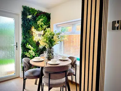 a dining room with a table and a green wall at Keswick Hot Tub Family House in Lytham St Annes
