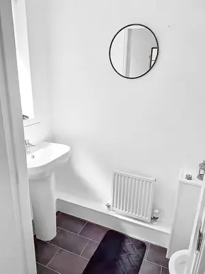 a white bathroom with a sink and a mirror at 3BR with Ensuite & Downstairs WC in Litherland