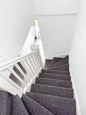 a staircase in a white building with grey carpet at 3BR with Ensuite & Downstairs WC in Litherland