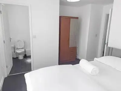 a white room with two beds and a toilet at 3BR with Ensuite & Downstairs WC in Litherland