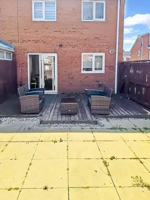 a patio with two chairs and a table and a building at 3BR with Ensuite & Downstairs WC in Litherland