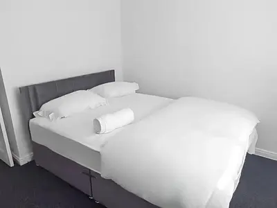 a bed with white sheets and pillows in a room at 3BR with Ensuite & Downstairs WC in Litherland