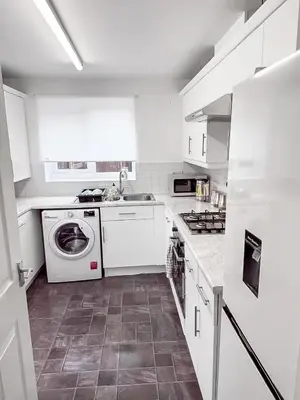 a kitchen with white cabinets and a washer and dryer at 3BR with Ensuite & Downstairs WC in Litherland