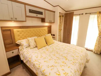 a bedroom with a bed with a yellow comforter at 22 Yealand in Carnforth