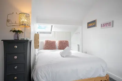 a bedroom with a white bed with pink pillows at Santiago Suites in Southport