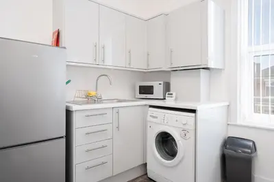a white kitchen with a washing machine and a microwave at Santiago Suites in Southport