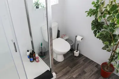 a bathroom with a toilet and a glass shower stall at Santiago Suites in Southport