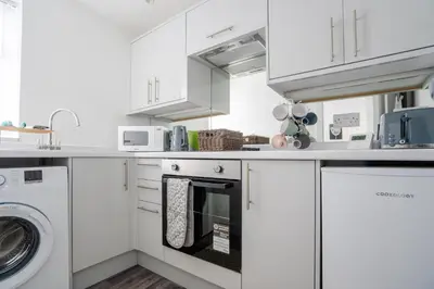 a kitchen with white cabinets and a washer and dryer at Santiago Suites in Southport