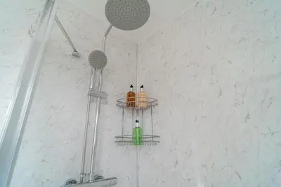 a bathroom with a shower with two shelves on the wall at Southport Retreat in Ainsdale