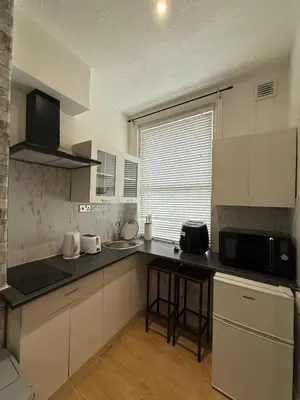 a kitchen with white cabinets and a black counter top at Almar Hotel Apartments Blackpool in Blackpool