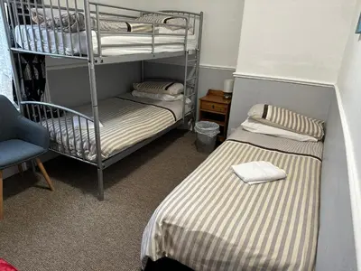 a room with two bunk beds and a chair at Tuxford House in Blackpool