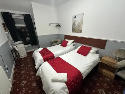 two beds in a hotel room with red and white sheets at Tuxford House in Blackpool