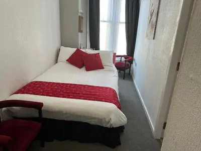 a hotel room with a bed with red pillows at Tuxford House in Blackpool