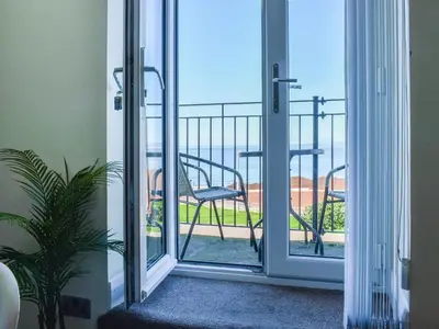 a room with a sliding glass door with a chair on a balcony at Beauty Abounds in Morecambe