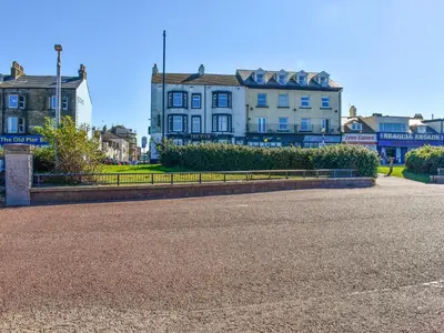 a street with a building in the background and a building with a fence at Beauty Abounds in Morecambe