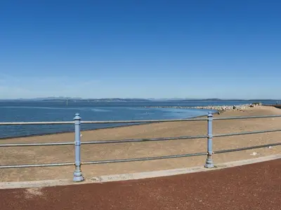 a fence on the beach with the ocean in the background at Beauty Abounds in Morecambe