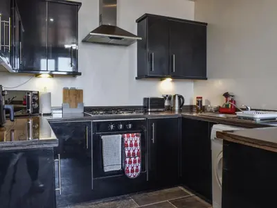 a kitchen with black cabinets and a stove top oven at Beauty Abounds in Morecambe