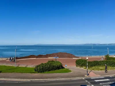 a person riding a bike down a road near the ocean at The Croston in Morecambe