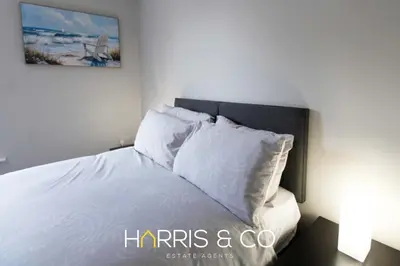 a bedroom with a bed with white sheets and pillows at Captain's Cove in Fleetwood