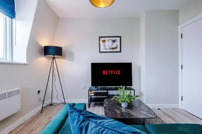 a living room with a blue couch and a tv at Elysée Suites - Stunning 1 Bed Flat in Southport in Southport