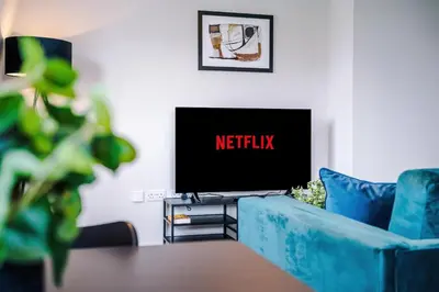 a living room with a tv and a blue couch at Elysée Suites - Stunning 1 Bed Flat in Southport in Southport