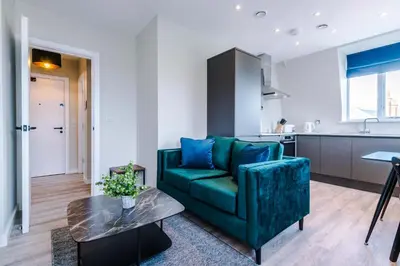 a living room with a green couch and a table at Elysée Suites - Stunning 1 Bed Flat in Southport in Southport