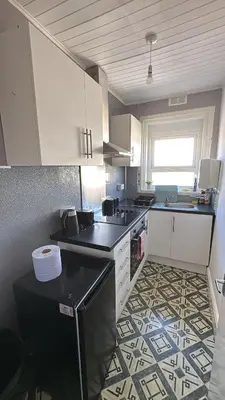 a kitchen with white cabinets and a tile floor at Blackpool Pleasure Beach whole Holiday Home! in Blackpool