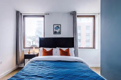 a bedroom with a blue bed with orange pillows at Newly renovated stylish studio Merseyside Moorfields in Liverpool
