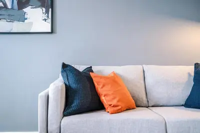 a couch with orange and blue pillows on it at Newly renovated stylish studio Merseyside Moorfields in Liverpool
