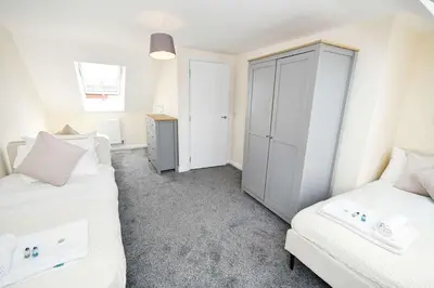 a bedroom with two white beds and a cabinet at Modern 3 Bedroom House in Kirkdale Liverpool in Liverpool