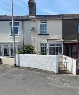 a white house with a white fence in front of it at Cosy, coastal cottage- Beach, Pub and shop nearby in Haverigg