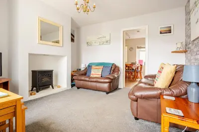 a living room with two leather chairs and a fireplace at Cosy, coastal cottage- Beach, Pub and shop nearby in Haverigg