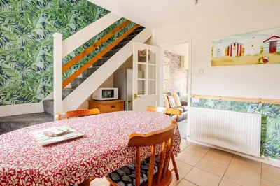 a dining room with a table and a staircase at Cosy, coastal cottage- Beach, Pub and shop nearby in Haverigg
