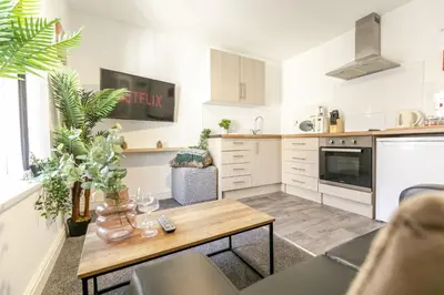 a kitchen with white cabinets and a wooden table at 1 Double Bedroom Apartment Central Blackpool 4 in Blackpool