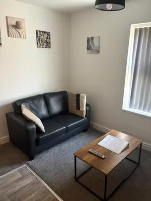 a living room with a black leather couch and a coffee table at 1 Double Bedroom Apartment Central Blackpool 4 in Blackpool