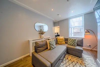a living room with a couch and a mirror at Stunning 1 Bedroom 4 Guest Flat by Anfield Stadium in Liverpool