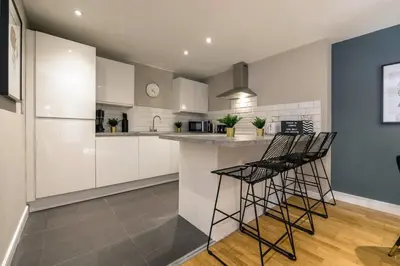 a kitchen with white cabinets and black bar stools at Central 2 Beds with Free Parking in Liverpool