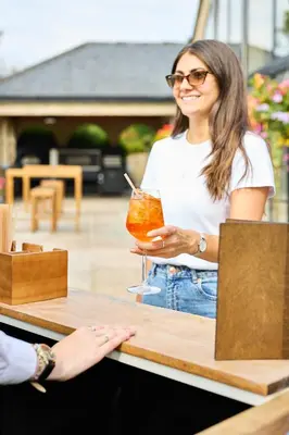 a woman sitting at a table with a drink at Longridge House in Longridge