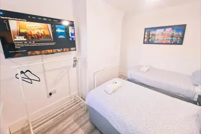 a small room with two beds and a flat screen tv at 5 star Luxury Home by Liverpool Football Stadium in Liverpool