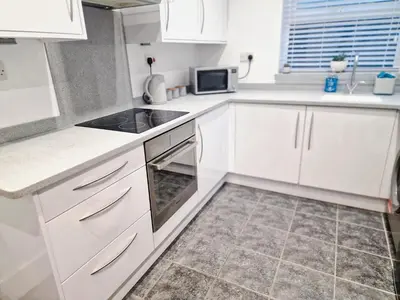 a kitchen with white cabinets and a stove top oven at 5 star Luxury Home by Liverpool Football Stadium in Liverpool