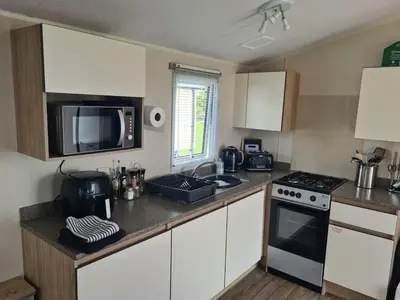 a kitchen with white cabinets and a stove and a microwave at The Seaflower - With Lake Views in Millom