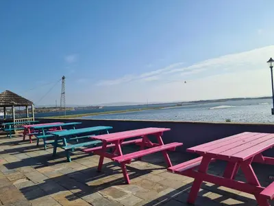 a row of picnic tables sitting next to the beach at The Seaflower - With Lake Views in Millom