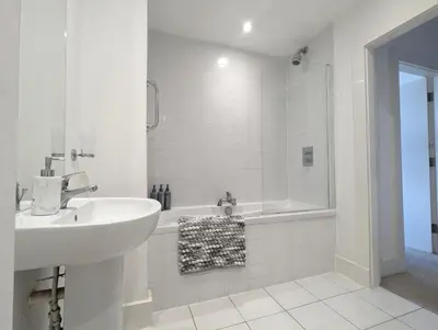 a white bathroom with a sink and a tub at Elegant Apartment in Hamilton Square Free Parking in Birkenhead