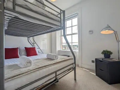 a bedroom with a bunk bed with white and red pillows at Elegant Apartment in Hamilton Square Free Parking in Birkenhead