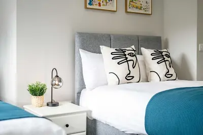 a bedroom with a bed with white sheets and black and white pillows at Two Apartments in One , City Centre, Sleeps 11! in Liverpool
