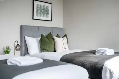 a bedroom with two beds with white and green pillows at Two Apartments in One , City Centre, Sleeps 11! in Liverpool