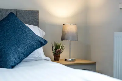 a bed with a blue pillow and a lamp on a table at Kemble House - Air Host & Stay - 5 Bedroom, 5 Bathroom - Sleeping 10 in Prescot